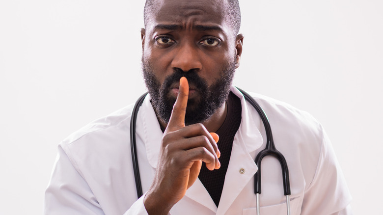A doctor with his index finger on his lips