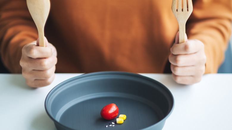 person with utensils and small food