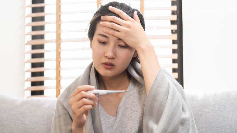 woman checking her temperature with a thermometer