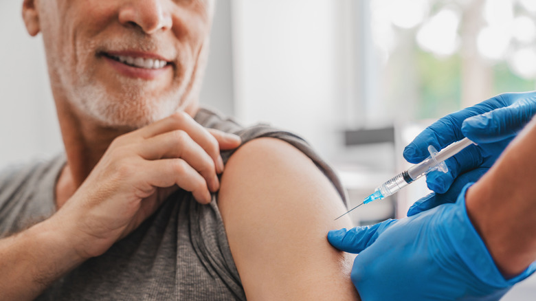 Person rolling up their sleeve and receiving a vaccine shot in their shoulder