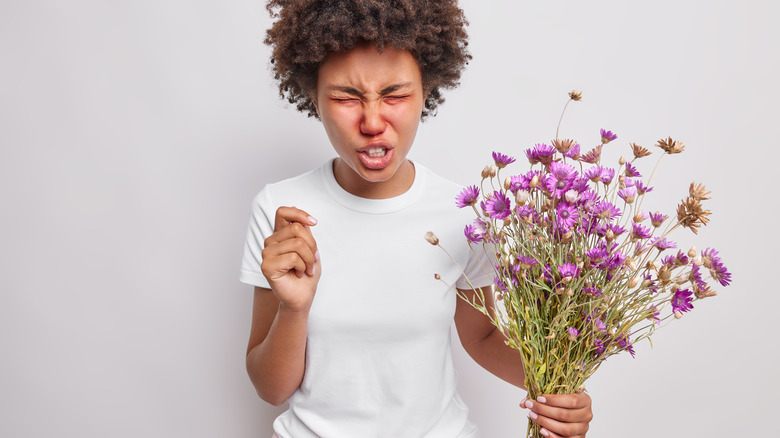 woman sneezing holding flowers