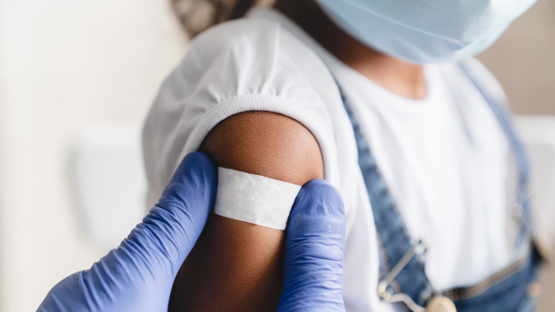 Child with vaccine bandage on arm