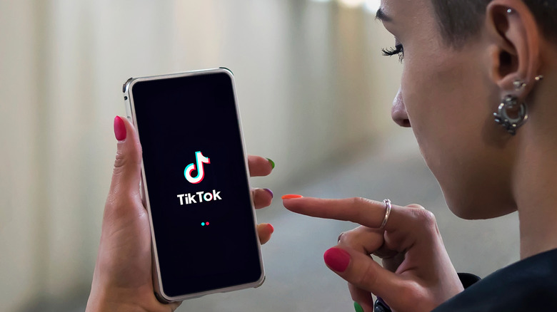 woman holding phone with TikTok app