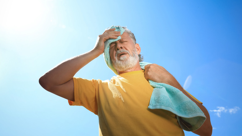 older man wiping his forehead in the extreme heat