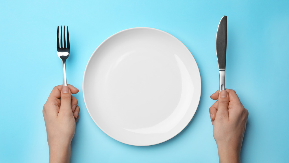 empty plate with fork and knife, light blue background