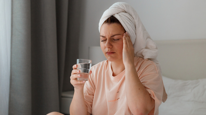 Wincing woman touching head in pain