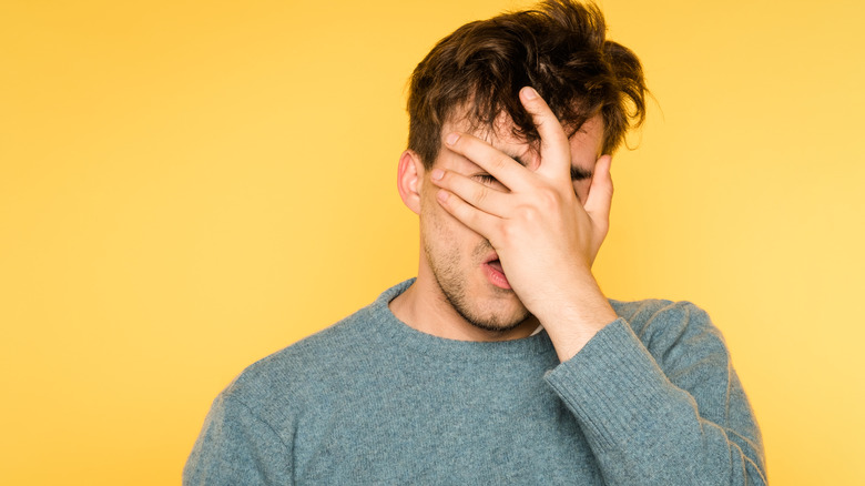 Man covering his face with his hand