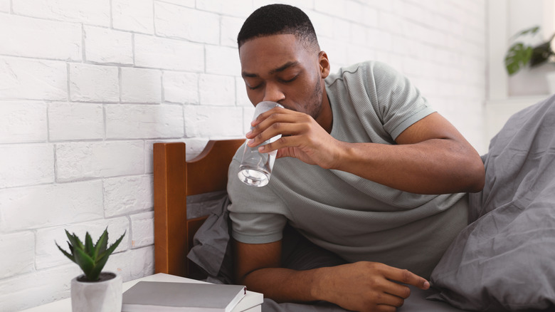 Man in bed drinking water