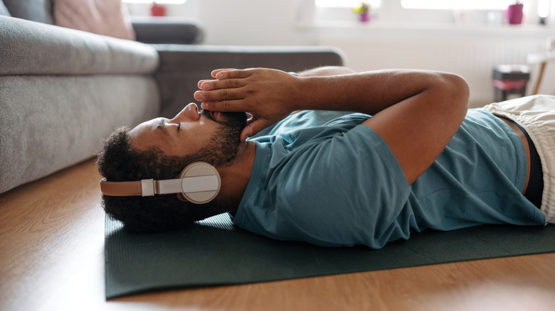 A man lying on the floor peacefully while wearing headphones