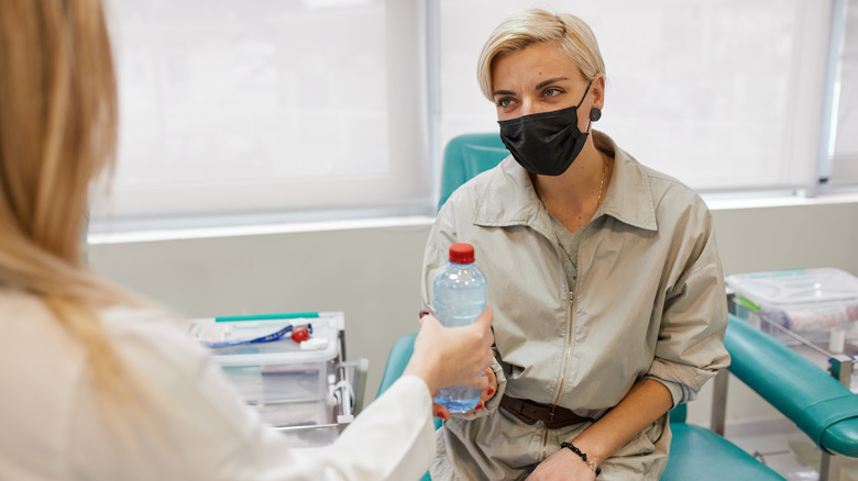 Doctor handing water bottle to blood draw patient