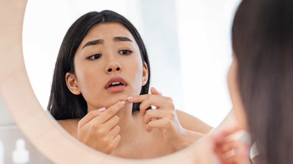 Woman examining pimple 