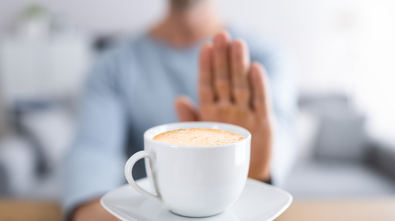 Hand saying no to cup of coffee