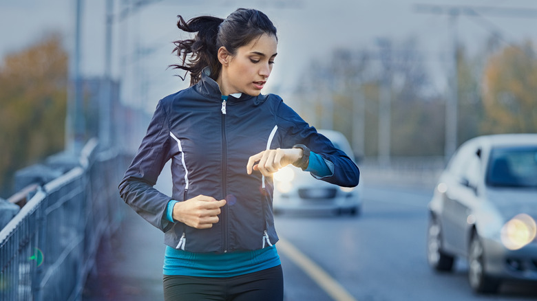 Woman running and looking down at her watch