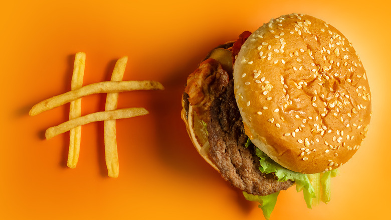 Hashtag made of fries next to a McDonald's Big Mac on yellow background