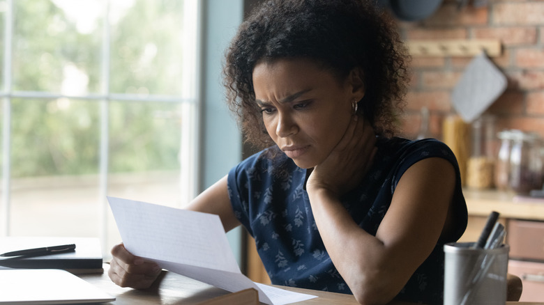 Woman reads letter with concern on face