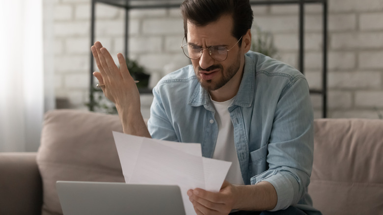 Man looks at bill in frustration