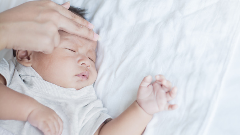 Mother holding fingers to baby's forehead