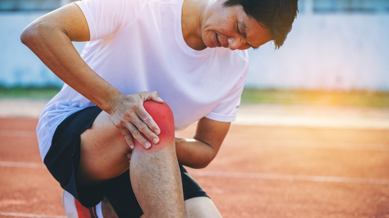 kneeling man holding sore knee