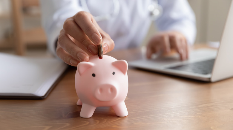 doctor putting coin in piggy bank