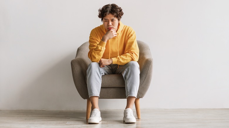 sad young man sitting with hand on chin