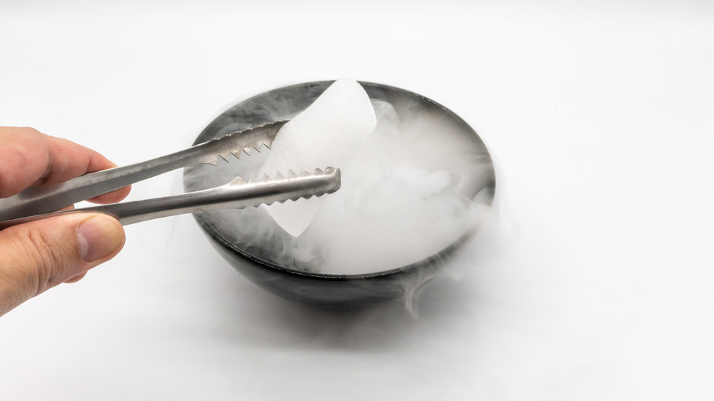 Closeup of a chunk of dry ice creating smoke in a bowl of water