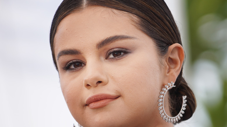 Selena Gomez outside wearing hoop earrings and hair pulled back in bun