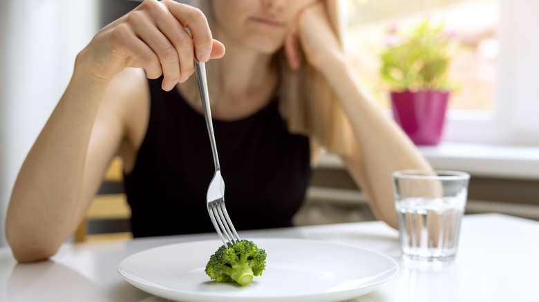 Woman looking at broccoli on plate