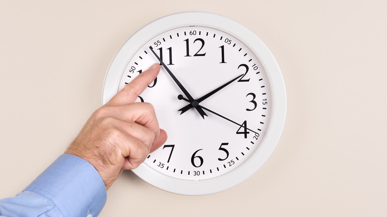man's hand changing the clock