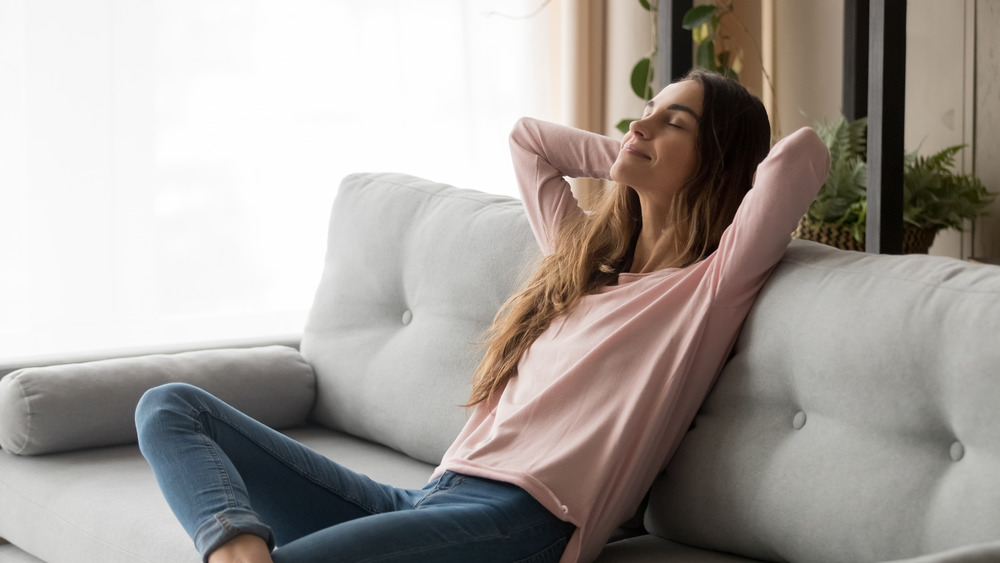 Woman leaning back and relaxing on a couch while smiling