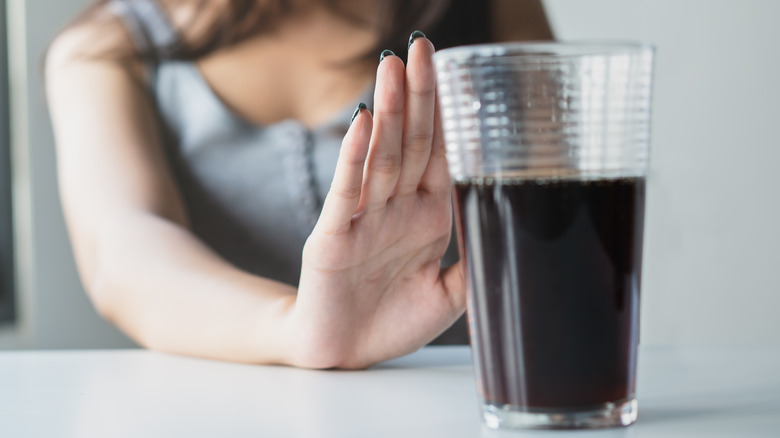 Woman pushing glass of soda away