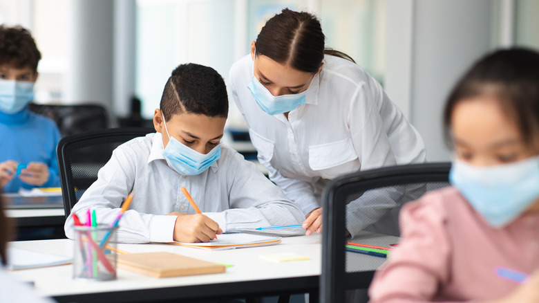 Teacher helps a student at desk