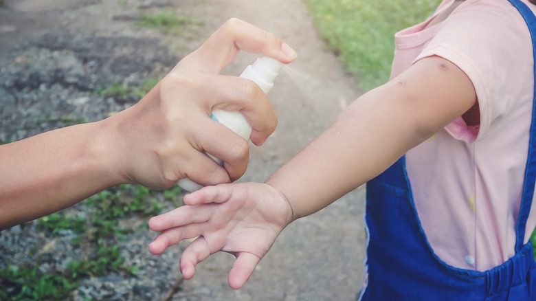 Woman spraying child with bug spray for mosquitoes