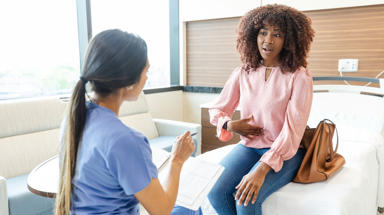 Woman with abdominal pain talking to doctor
