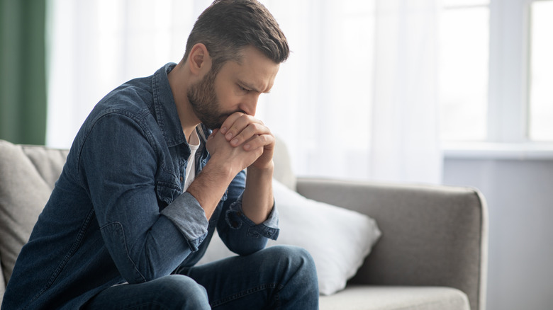 Upset man deep in thought with hands clasped against his face