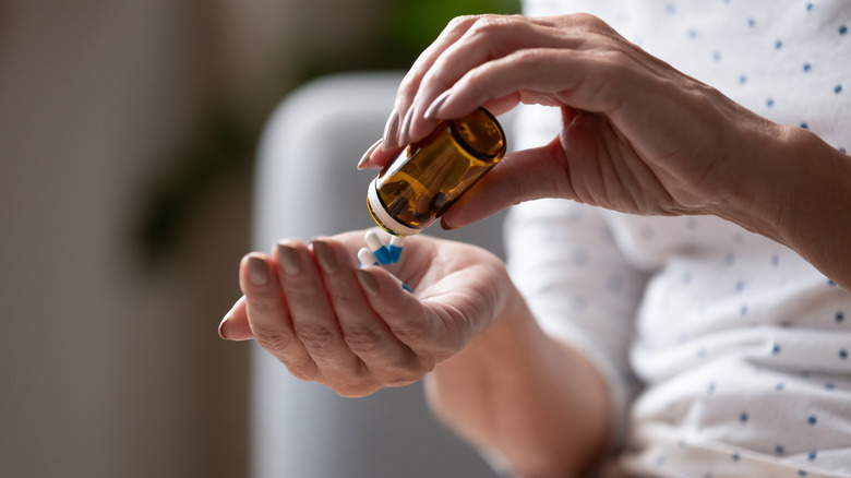 person pouring pills out of bottle