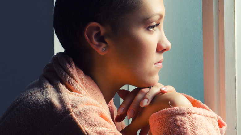 young woman with cancer looking out window