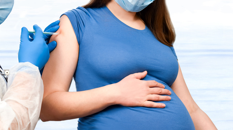 Close up of pregnant woman wearing a mask and receiving COVID-19 vaccine