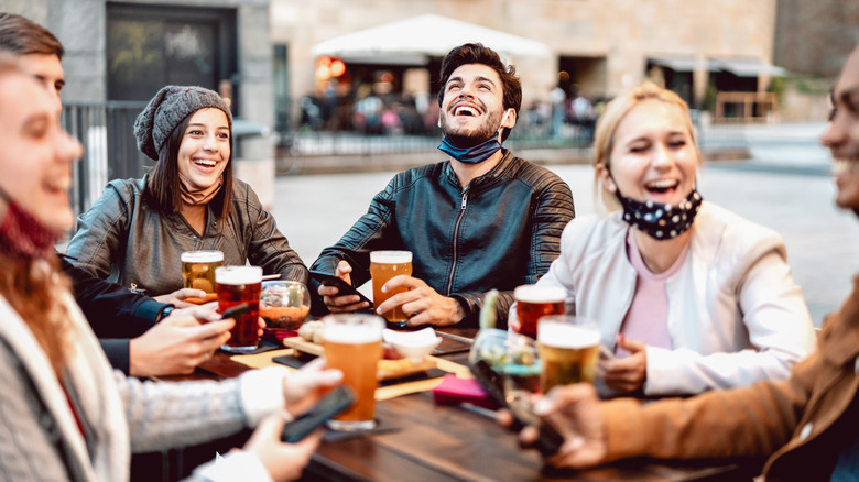 friends laughing and drinking, masks down