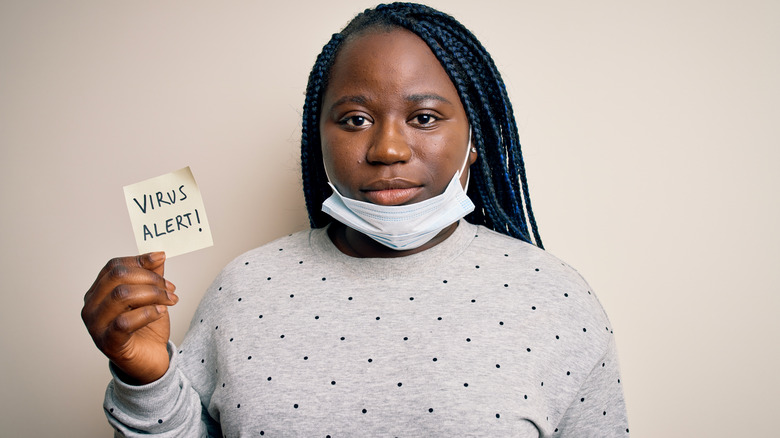 girl with mask down holding note