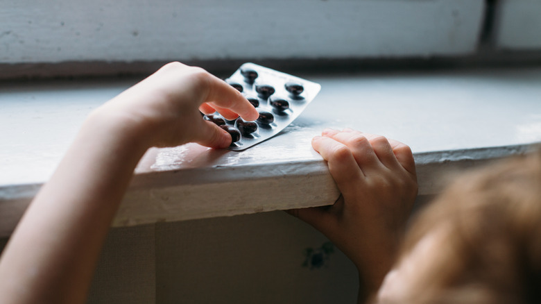 Child's hand reaching for pills