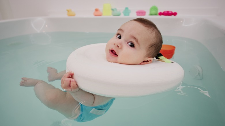 Baby floating in a bathtub wearing a neck float device