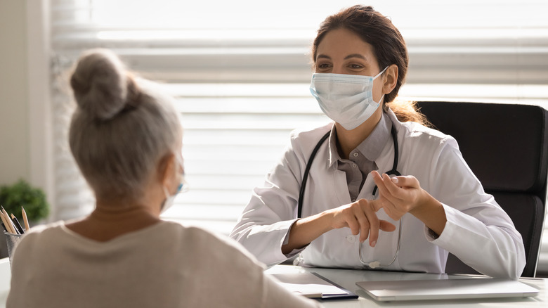 Masked doctor speaking to masked patient