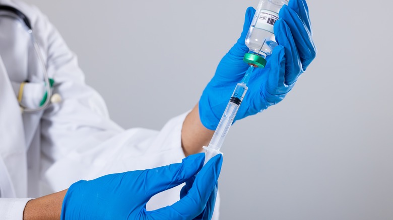 Syringe drawing drug from vial