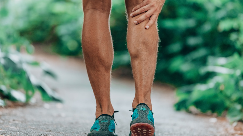 Man massaging sore calf muscles during running training.