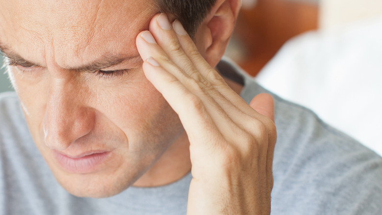 man touching left side of head