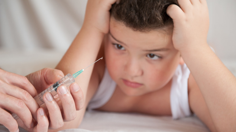 Doctor holding syringe in front of boy