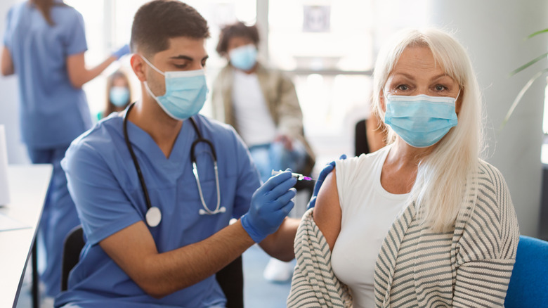 Older masked woman receiving vaccine
