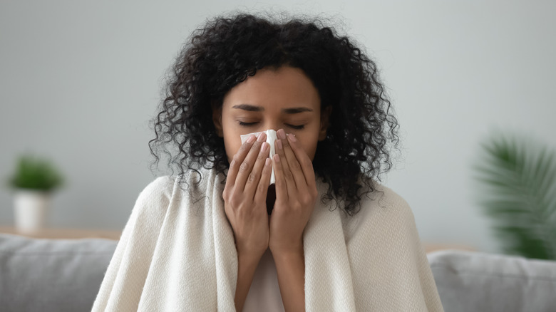 Sick woman blowing nose