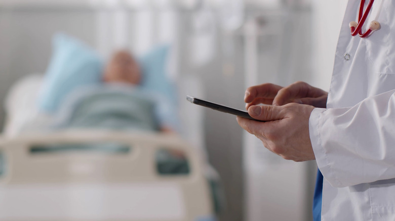 doctor's hand with senior patient in background