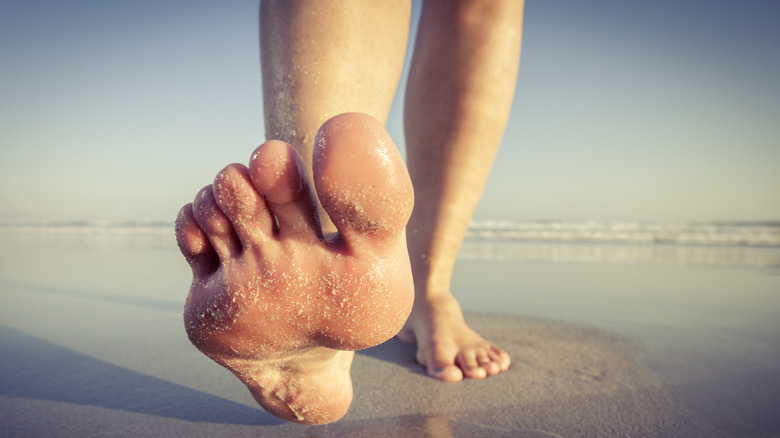 pair of feet walking on sand at beach